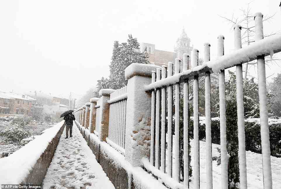 Eine Person geht am Montag in der Nähe des Palastes Cartoixa de Valdemossa im schneebedeckten Bergdorf Valldemossa auf Mallorca spazieren