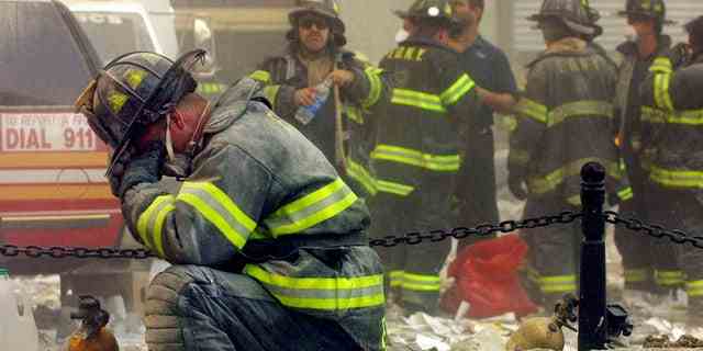 Ein Feuerwehrmann bricht zusammen, nachdem die Gebäude des World Trade Centers am 11. September 2001 einstürzten, nachdem zwei entführte Flugzeuge bei einem Terroranschlag in die Zwillingstürme eingeschlagen waren.  (Foto von Mario Tama/Getty Images)