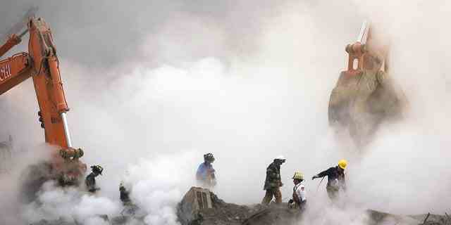 Feuerwehrleute bahnen sich ihren Weg durch Rauchwolken über die Ruinen, während die Arbeiten am Ground Zero in New York fortgesetzt werden, einen Monat nach den Anschlägen auf das World Trade Center am 11. Oktober 2001. 