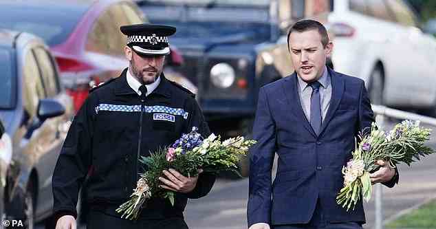Sussex Police Chief Superintendent James Collis (left) and Metropolitan Police Detective Superintendent Lewis Basford (right) carry floral tributes on Golf Drive in Brighton