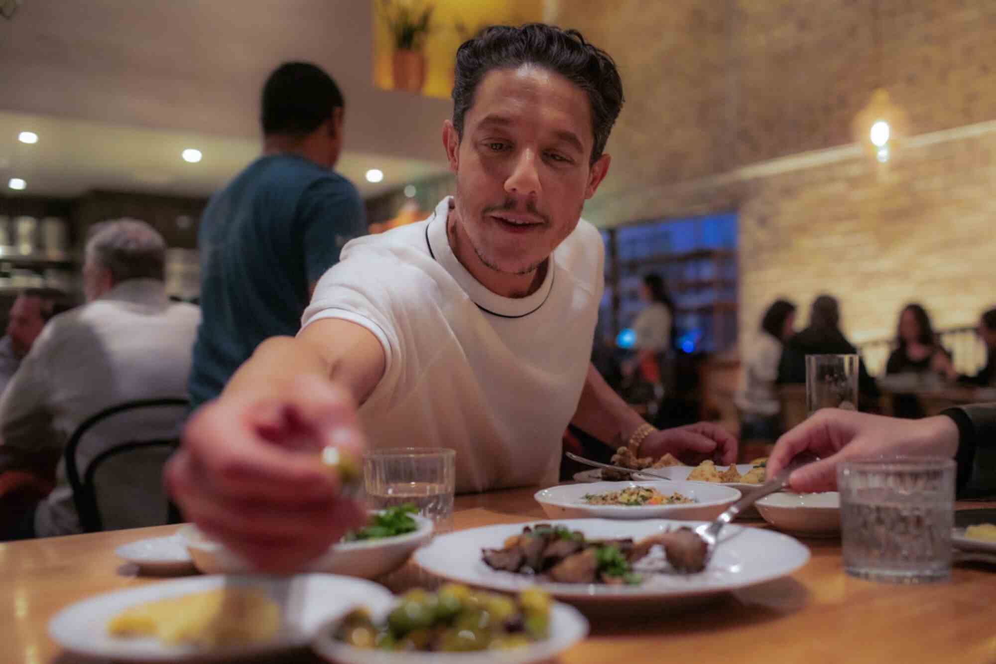 Ein Mann greift in einem Restaurant nach den Oliven. 