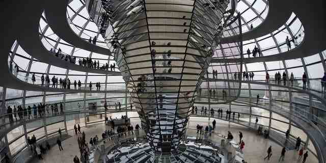 Besucher stehen in der Kuppel des Deutschen Bundestages in Berlin.