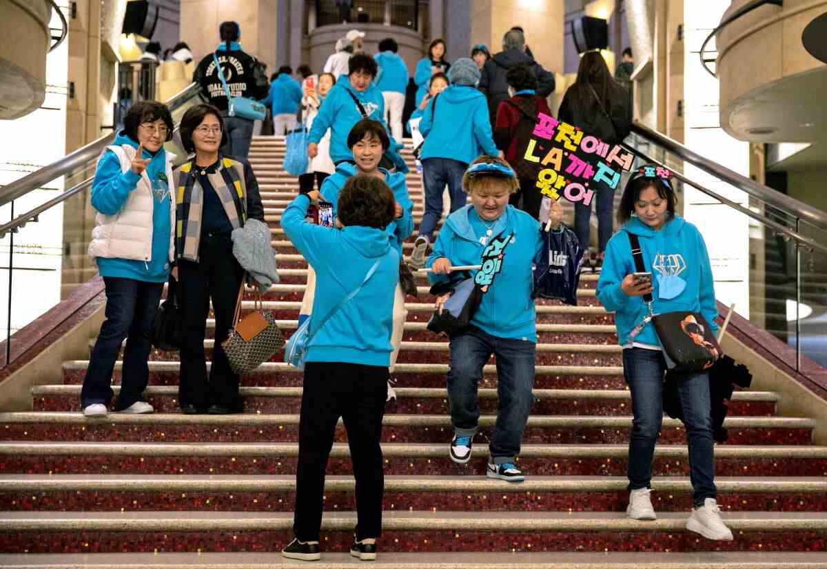 Eine Gruppe von Menschen in blaugrünen Sweatshirts steigt eine breite Treppe hinab. 