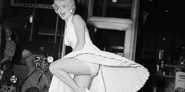 Filmstar Marilyn Monroe posiert über einem U-Bahn-Gitter in Manhattan, während der Wind ihr weißes Kleid hochbläst.  Fotografen fangen den Moment mit der Kamera ein, der am 16. September 1954 während der Dreharbeiten zu stattfindet "Siebenjähriges Jucken." Berichten zufolge war Monroes Ehemann Joe DiMaggio unzufrieden mit der Aufmerksamkeit, die seine Frau von der Menge erhielt.
