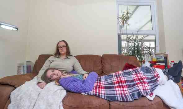 Zwei Mädchen auf einem Sofa, das eine über die Beine des anderen geführt