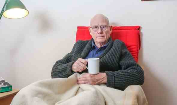 Ein älterer Mann saß auf einem Stuhl und hielt eine Tasse