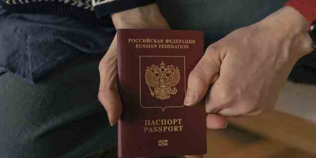 Die russische Marina zeigt ihren russischen Pass, während sie in einem Hostel in Belgrad für ein Foto posiert.