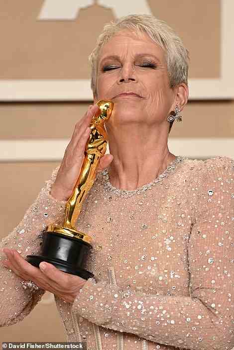 Sweet: Curtis posed with her shiny new trophy in the press room as she let the new Oscar kiss her chin
