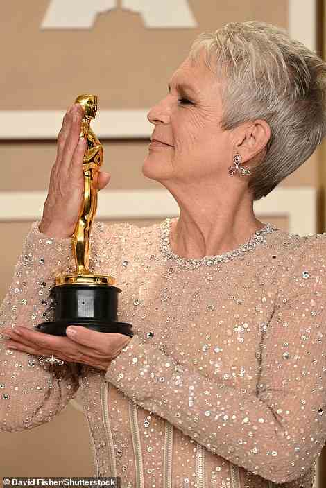 Sweet: Curtis posed with her shiny new trophy in the press room as she let the new Oscar kiss her chin