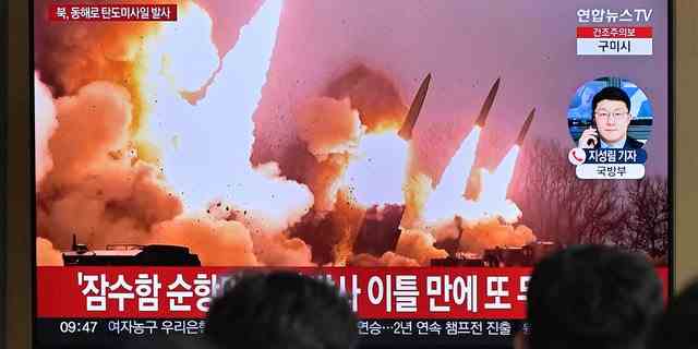 Menschen stehen am 14. März 2023 in einem Bahnhof in Seoul neben einem Fernseher, der eine Nachrichtensendung mit Dateiaufnahmen eines nordkoreanischen Raketentests zeigt. 