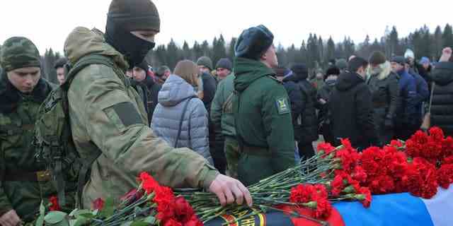 Ein Mann legt Blumen während der Beerdigung von Dmitri Menschikow, einem Söldner der Wagner-Gruppe, der während des militärischen Konflikts in der Ukraine getötet wurde, in der Gasse der Helden auf einem Friedhof in Sankt Petersburg, Russland, am 24. Dezember 2022 nieder.
