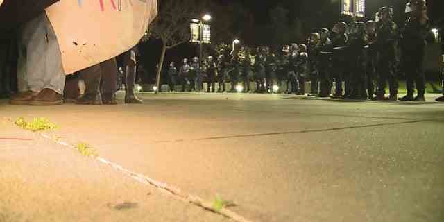 Eine Reihe von Polizisten hindert Demonstranten am 14. März 2023 daran, das University Credit Union Center an der UC Davis zu betreten.