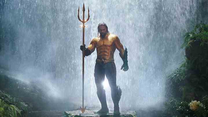 Aquaman steht im Film Aquaman vor einem Wasserfall und hält einen Dreizack.