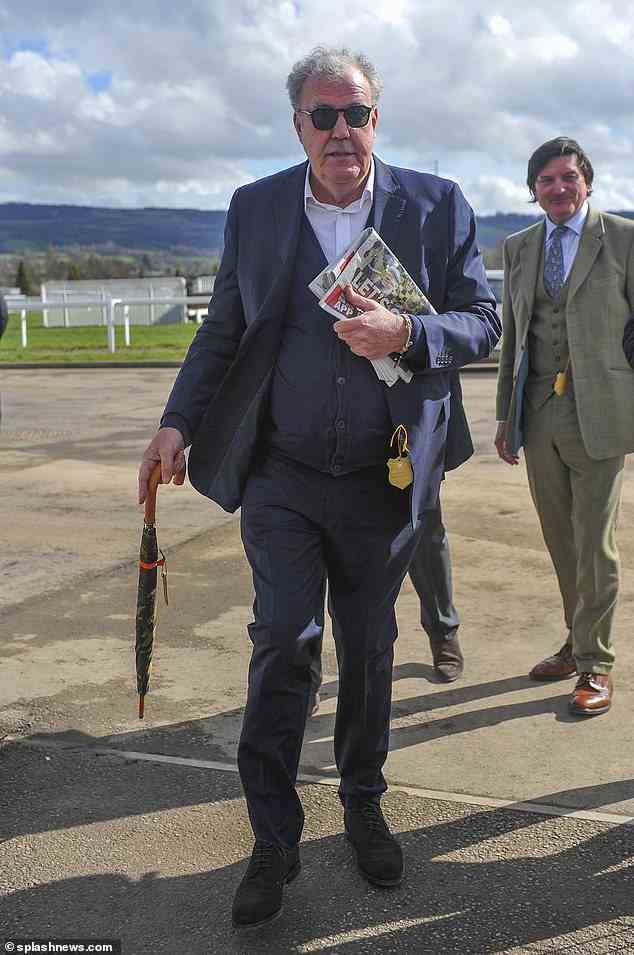 Clarkson holds a newspaper and an umbrella as he arrives at Cheltenham for the Gold Cup