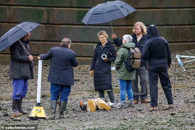 Zurück zum Thema: Cast und Crew umringten das Gebiet, während sie die neuen Szenen drehten, bekleidet mit Regenschirmen