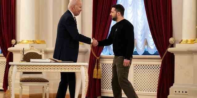 Der ukrainische Präsident Wolodymyr Selenskyj (rechts) und Präsident Biden geben sich am 20. Februar 2023 im Mariinsky-Palast bei einem unangekündigten Besuch in Kiew, Ukraine, die Hand.