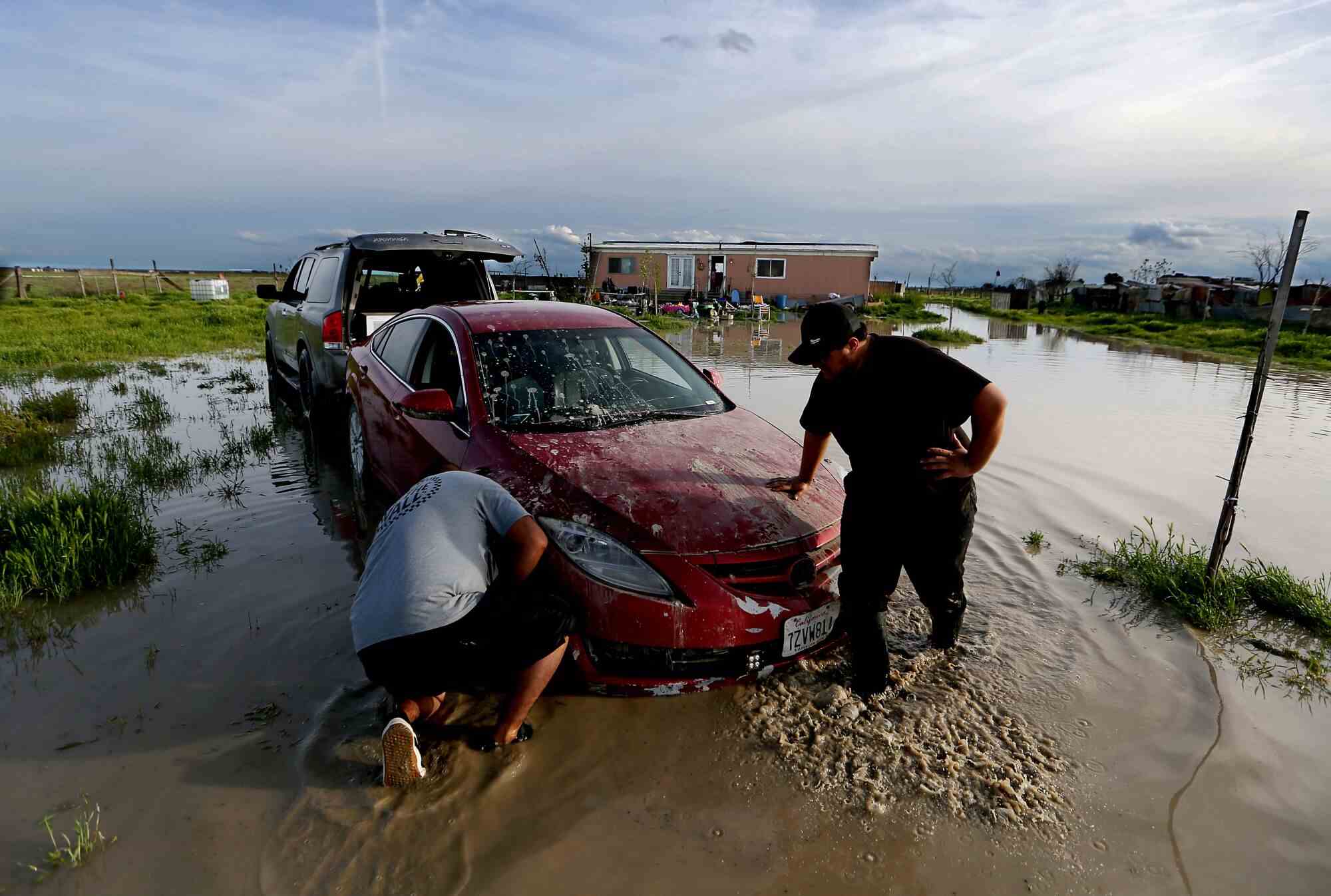 Jairo Estrada, links, und Juan Espinoza arbeiten daran, ein Auto ihrer Familie von ihrem überfluteten Grundstück in Allensworth zu holen.