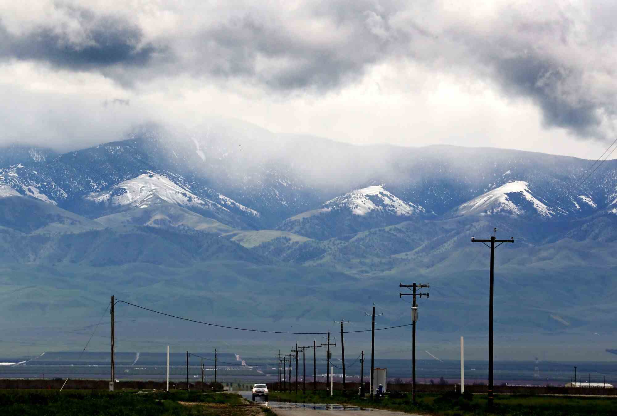 Gewitterwolken hinterlassen Schnee auf den Bergen am Rande des weiten und fruchtbaren San Joaquin Valley. 