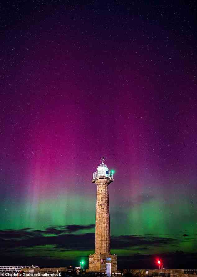 Whitby West Pier Lighthouse is lit up with the fluorescent pink and green of the aurora last night