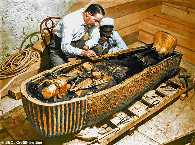 Pictured: Howard Carter and a colleague  cleaning the coffin of young Pharaoh Tutankhamun