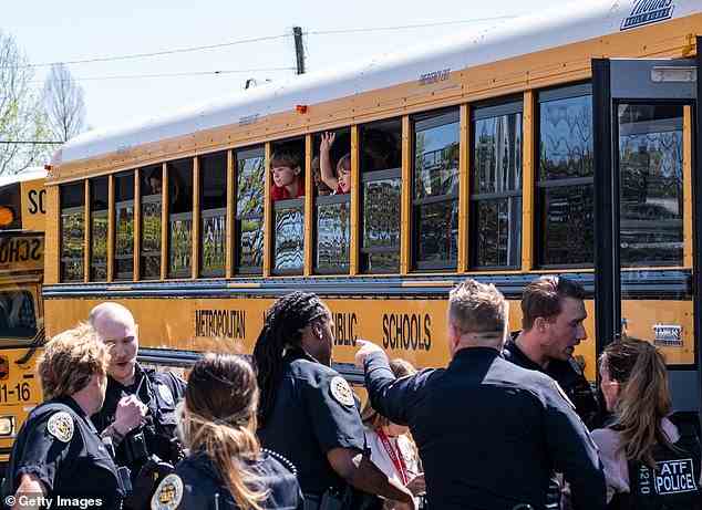 Verängstigte Kinder spähen aus den Fenstern ihres Schulbusses, während sie darauf warten, nach der Schießerei von der Schule weggefahren zu werden