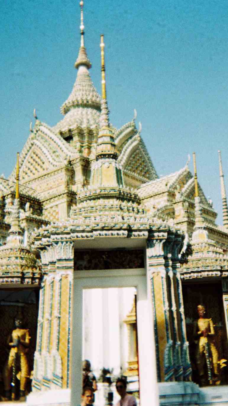 A series of decorative buildings — with tall spires and intricately carved ornamentation — stand together at Wat Pho, in Bangkok.