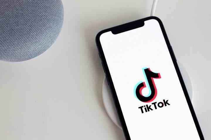 Ein Smartphone und zwei weitere Geräte auf einem weißen Tisch.  Das Smartphone hat das TikTok-Logo auf seinem Bildschirm.