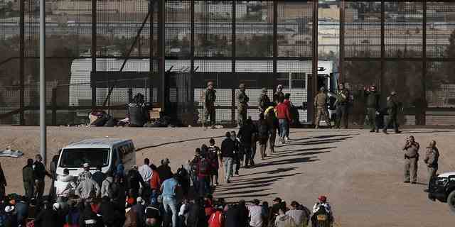 Migranten gehen in US-Gewahrsam, nachdem sie am 29. März 2023 die Grenze von Ciudad Juarez, Mexiko, überquert haben. Einen Tag zuvor starben Dutzende von Migranten bei einem Brand in einem Internierungslager für Migranten in Ciudad Juarez.