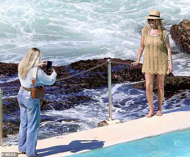 Sonne bekommen?  Sie trug einen passenden Strohhut in ihrem Strandensemble, als sie neben den Wellen posierte
