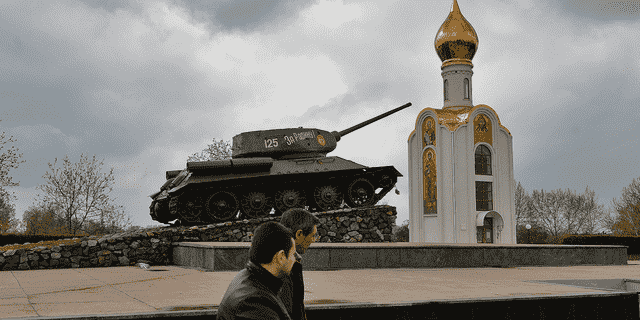 Menschen gehen im April 2014 in Tiraspol, der Hauptstadt der separatistischen Region Transnistrien in Moldawien, an einem Panzer aus der Sowjetzeit vorbei, der heute ein Denkmal ist, das den Sieg der Roten Armee gegen das faschistische Deutschland feiert.