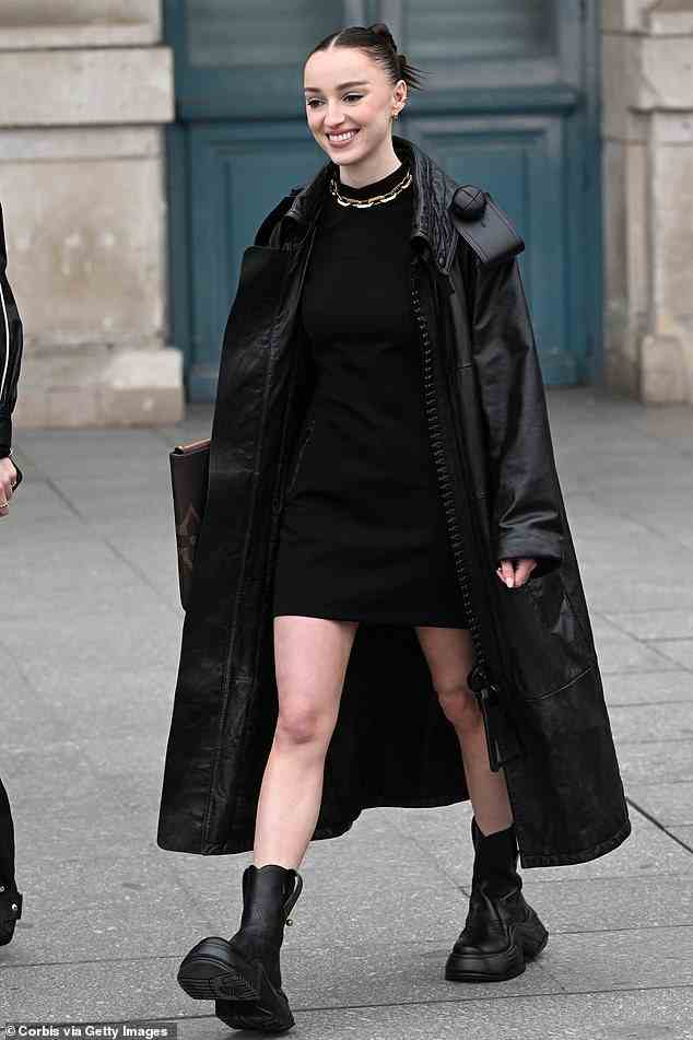 Langbeinig: Phoebe Dynevor erschien am Montag bei der mit Stars besetzten Louis Vuitton Paris Fashion Week Show und sah in einem einfachen schwarzen Minikleid mit klobigen Stiefeln umwerfend aus