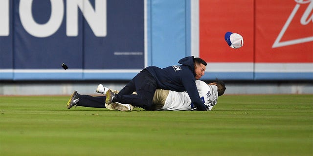 Ein Dodger-Fan wird von Sicherheitskräften angegriffen, als er versucht, seiner Freundin auf der Tribüne während des MLB-Spiels zwischen den Arizona Diamondbacks und den Los Angeles Dodgers am 30. März 2022 im Dodger Stadium in Los Angeles, CA, einen Vorschlag zu machen. 