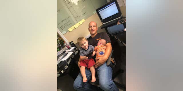 Drew Schock, Kailas Partner und Vater der Kinder, hält seine Kinder im Arm.