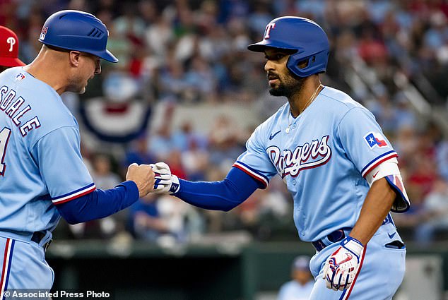 Texas Rangers' Marcus Semien, right, fist-bumps first base coach Corey Ragsdale after hitting a single in the bottom of the first inning