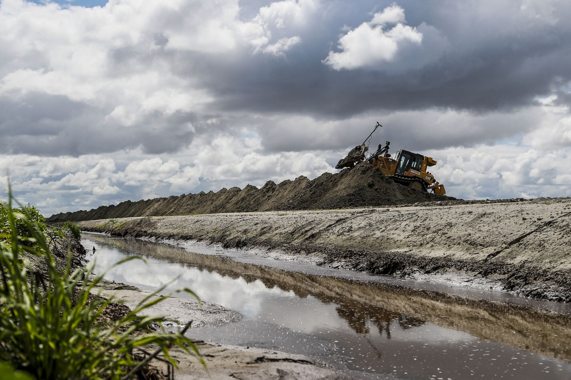 Ein Bulldozer schüttet Erde entlang eines Bewässerungsgrabens auf.