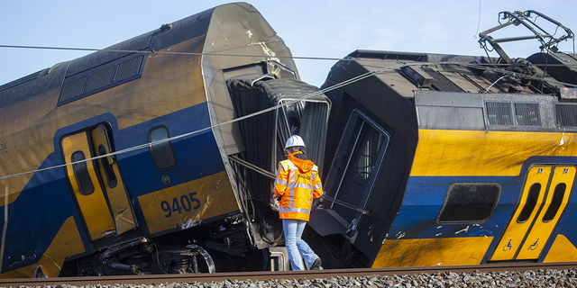 Ein niederländischer Bahnbeamter inspiziert die Unfallstelle, nachdem ein Zug am 4. April 2023 in Voorschoten, Niederlande, mit einem Baukran zusammengeprallt war.