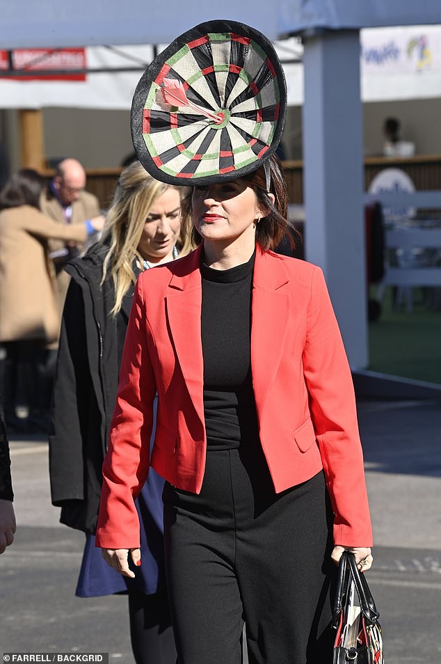 Diese mutige Fashionista kam mit einem Hut in Form einer Dartscheibe zu der Veranstaltung.  Sie ergänzte die Farben des Hutes mit einem roten Blazer und einer schwarzen Hose