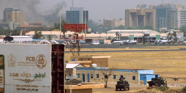 Militärfahrzeuge sind am 15. April 2023 inmitten von Zusammenstößen in der Stadt als Rauchschwaden über Gebäuden in der Nähe des Flughafens Khartum zu sehen.