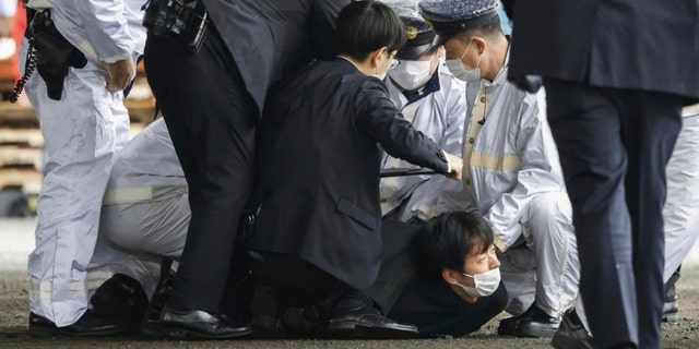 Ein mutmaßlicher Verdächtiger mittig am Boden wird von der Polizei erwischt, nachdem er angeblich geworfen hat "das verdächtige Objekt," als der japanische Premierminister Fumio Kishida am Samstag, den 15. April 2023, den Hafen von Saikazaki für eine Wahlkampfveranstaltung in Wakayama, Westjapan, besuchte. 