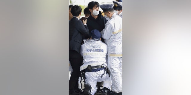 Ein Mann, Mitte, wird erwischt, nachdem am Samstag, dem 15. April 2023, eine Rauchbombe auf einen Hafen in Wakayama, Westjapan, geworfen wurde. 