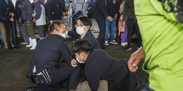 Ein Mann, der eine Rauchbombe geworfen hat, wird am Samstag, den 15. April 2023, in einem Hafen in Wakayama, Westjapan, festgenommen. 