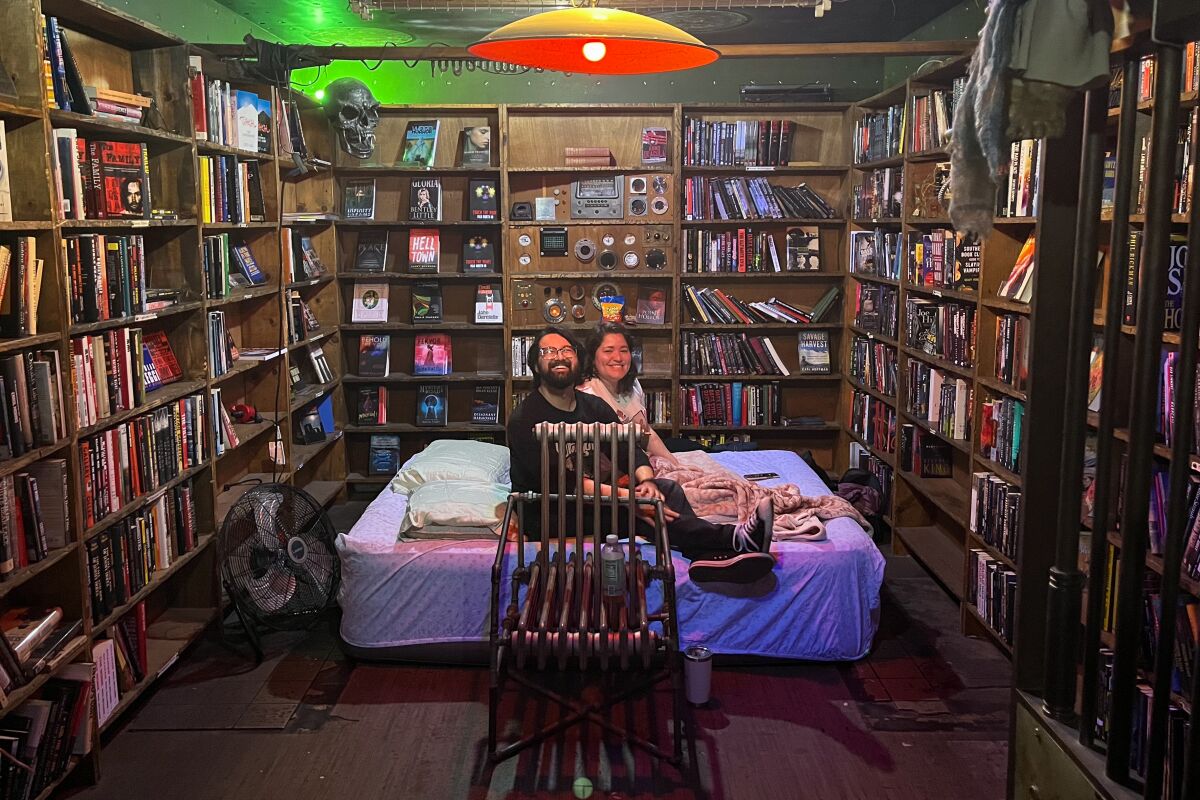 Ein Paar baut seine Luftmatratze inmitten von Bücherregalen auf.