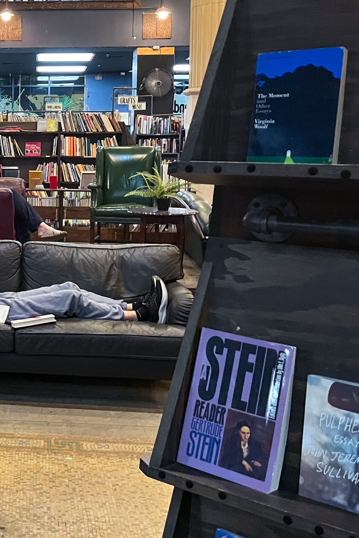 Eine Person liest auf einer Couch in der Mitte eines Buchladens.