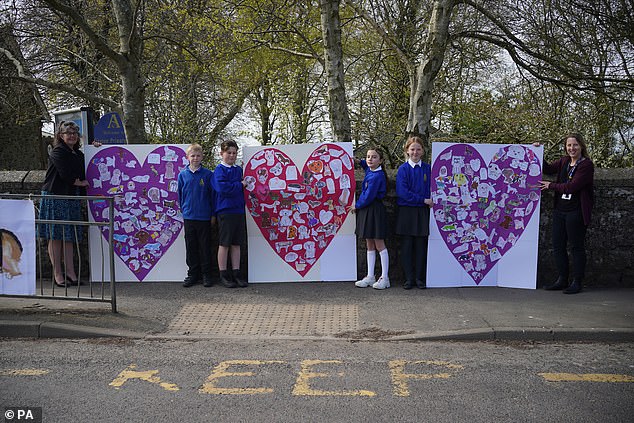Pupils and teachers from Aldington Primary School pay their respects to Paul O'Grady with picture collages of their drawings of dogs along the route of his funeral