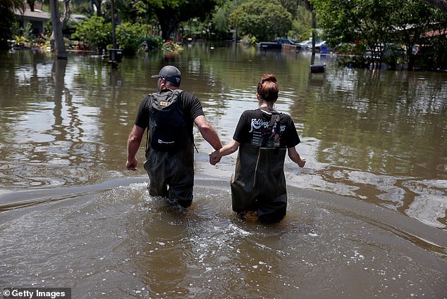 Chris Caywood und Heather Caywood gehen zu ihrem Haus, das am 14. April 2023 in Fort Lauderdale, Florida, von Hochwasser überschwemmt wurde