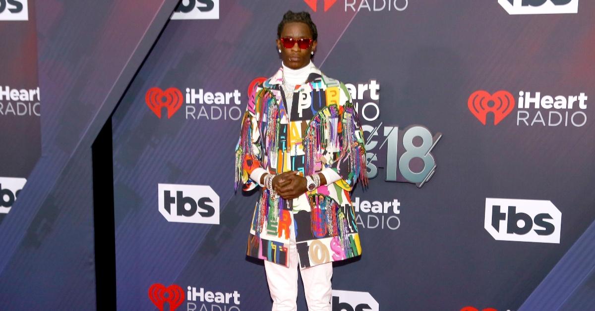 Young Thug posiert in einer farbenfrohen Jacke und Sonnenbrille bei den iHeartRadio Music Awards 2018. 