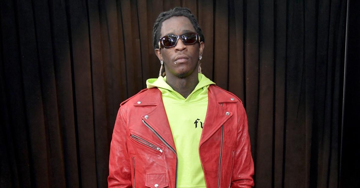 Young Thug mit neongrünem Hoodie, roter Jacke und Sonnenbrille auf. 