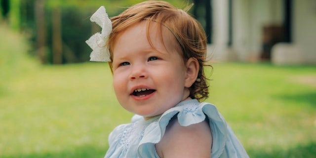 Der Herzog und die Herzogin von Sussex teilten das erste Foto von Tochter Lilibet, die in einem blauen Kleid mit einer weißen Schleife in ihren leuchtend roten Haaren lächelte