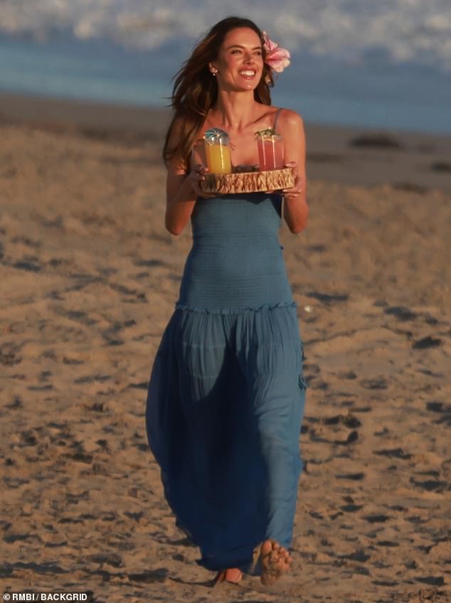 Strandtag: Das 42-jährige Model sah aus, als wäre sie bereit für ein Luau in einem blauen Maxikleid mit Spaghettiträgern und einer rosa Sternguckerlilie im Haar