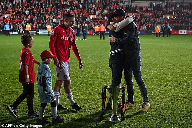 Big hug: Paul Mullin approaches Rob McElhenney and Ryan Reynolds as they embrace after Wrexham FC's big win